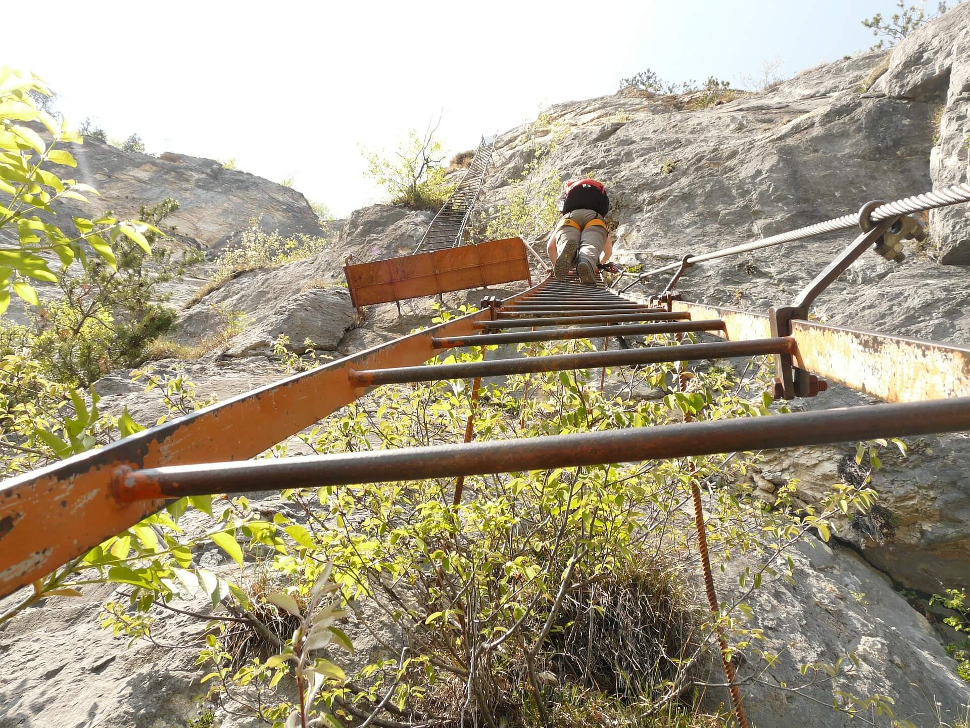 Looking up at someone climbing a ladder up a mountain