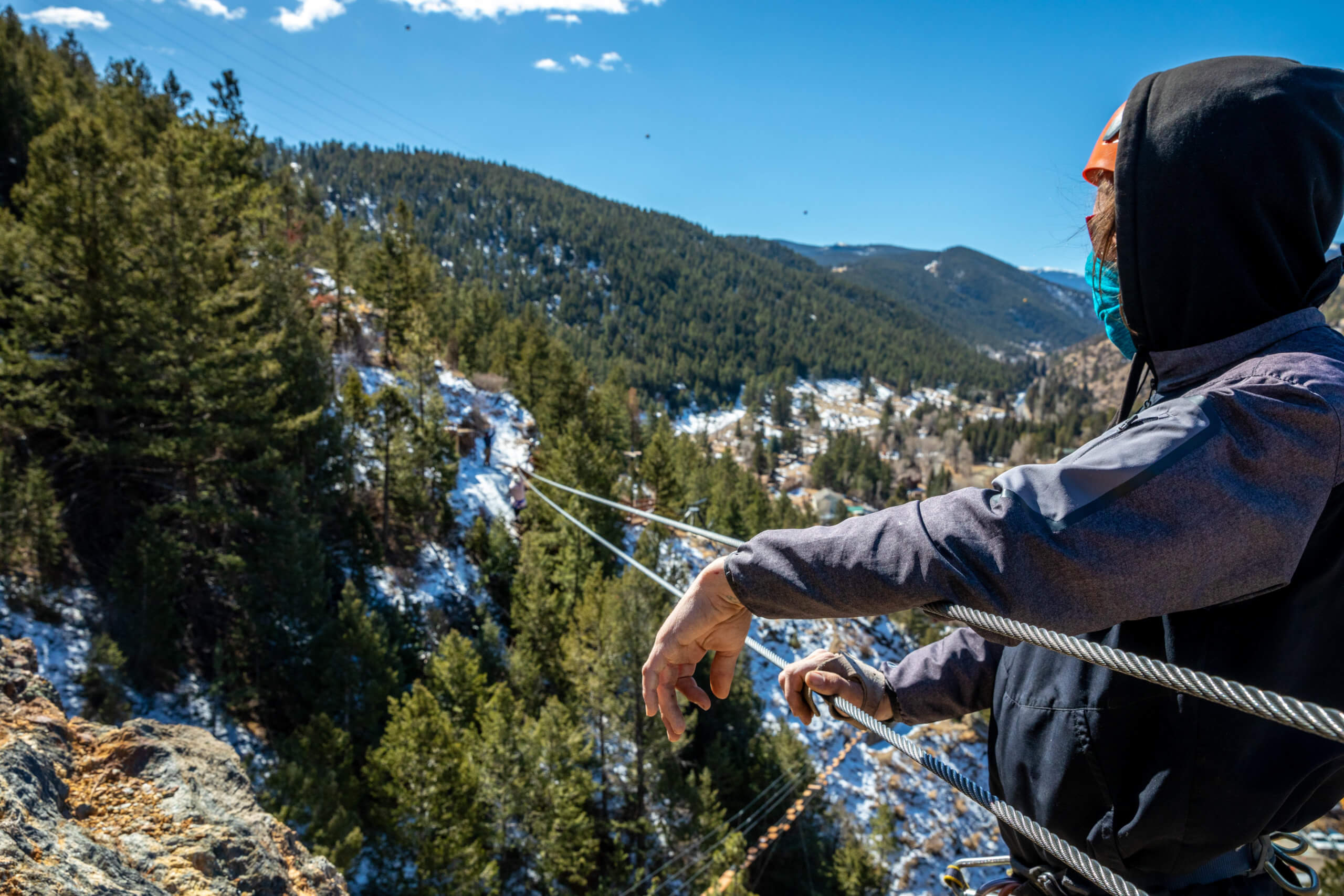 A guide looking down a zipline with a snowy mountain in the background