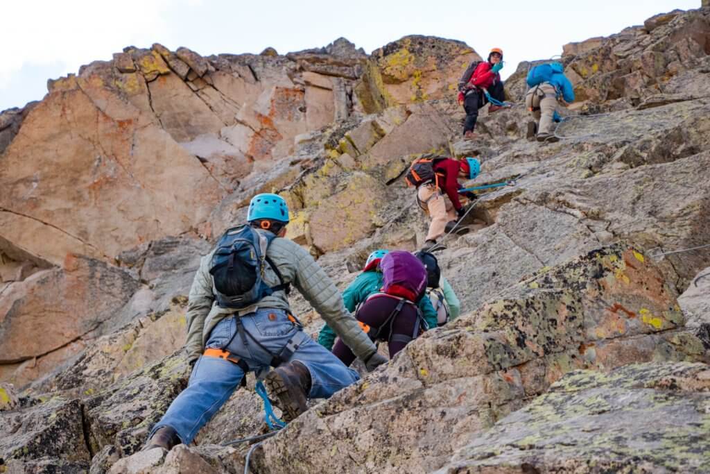 A group of people on Arapahoe Basin's via ferrata climbing up a rock