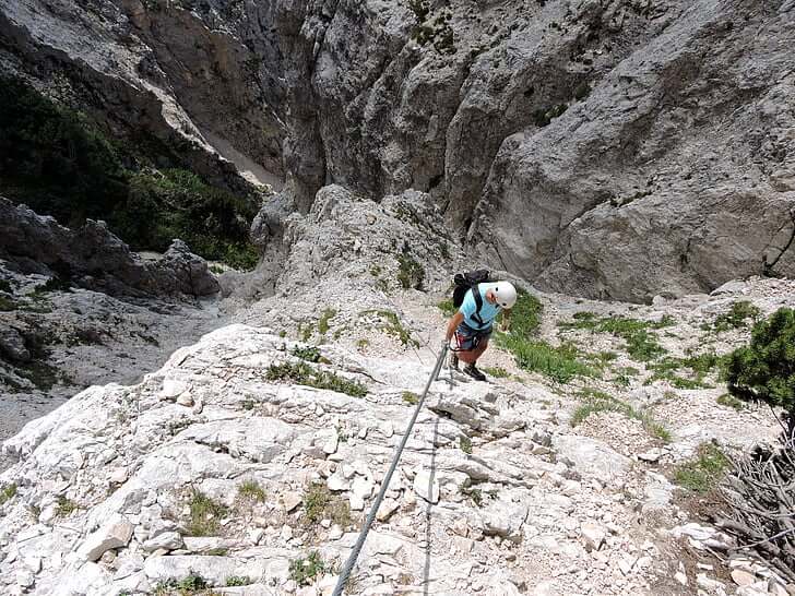 Man rappelling down during a Via Ferrata course in Italy