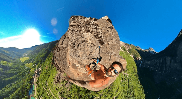 Man on the top of a mountain doing via ferrata with a gopro 360 taking a photo