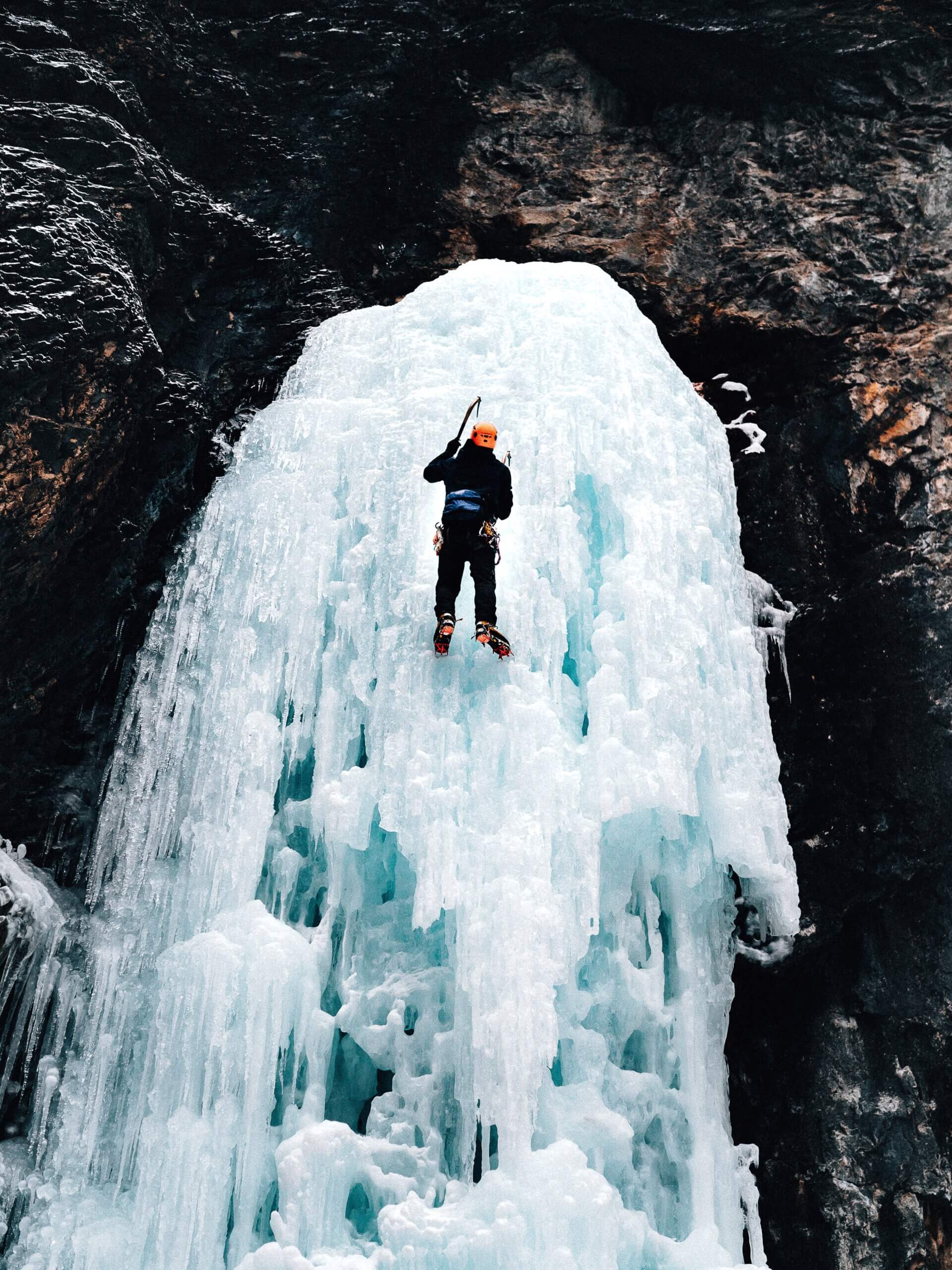 person climbing icy waterfall