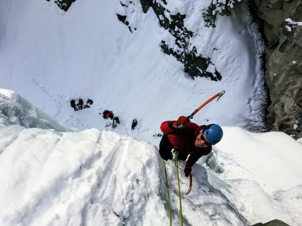 man ice climbing with ice pick