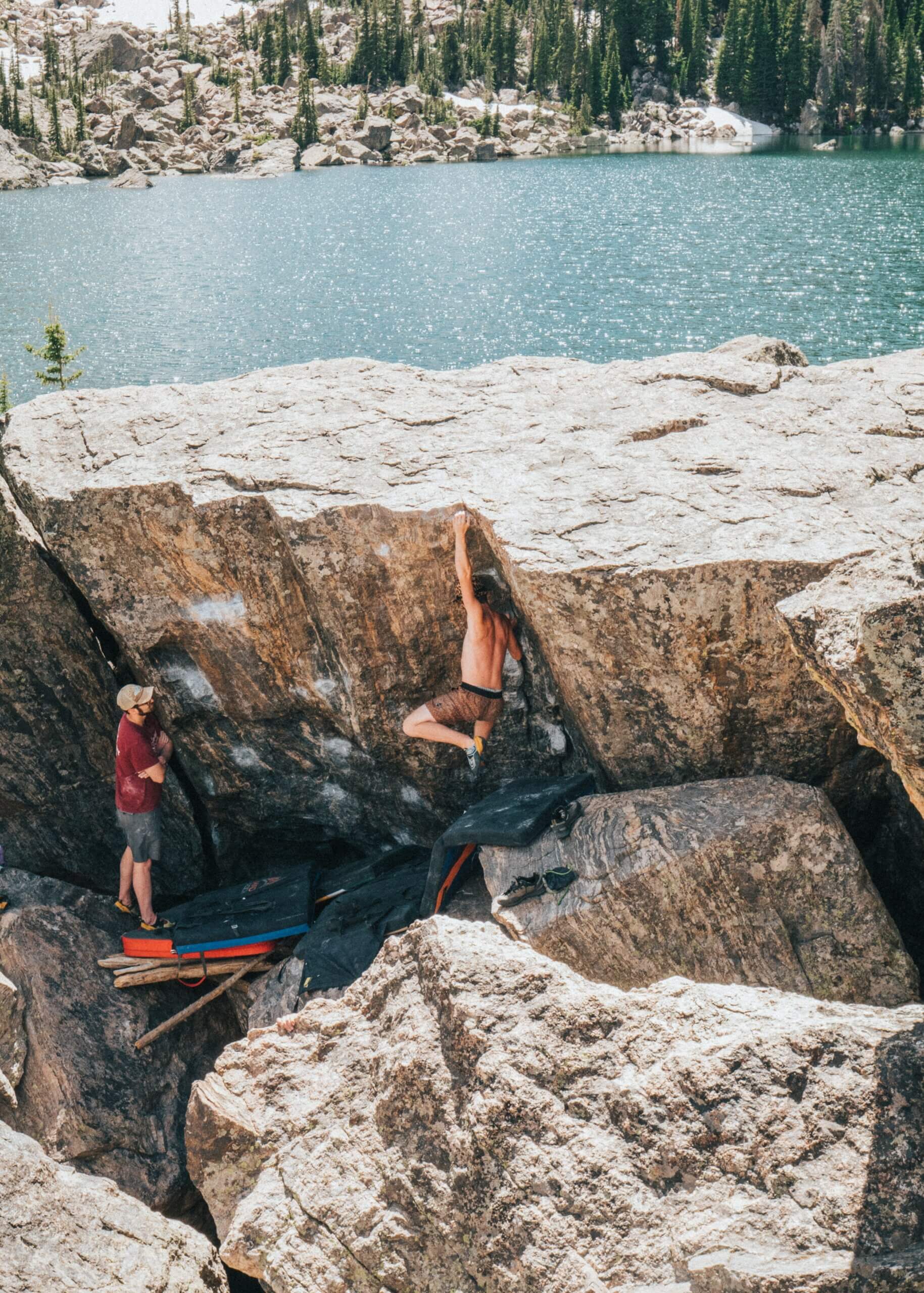 two men bouldering by alpine lake