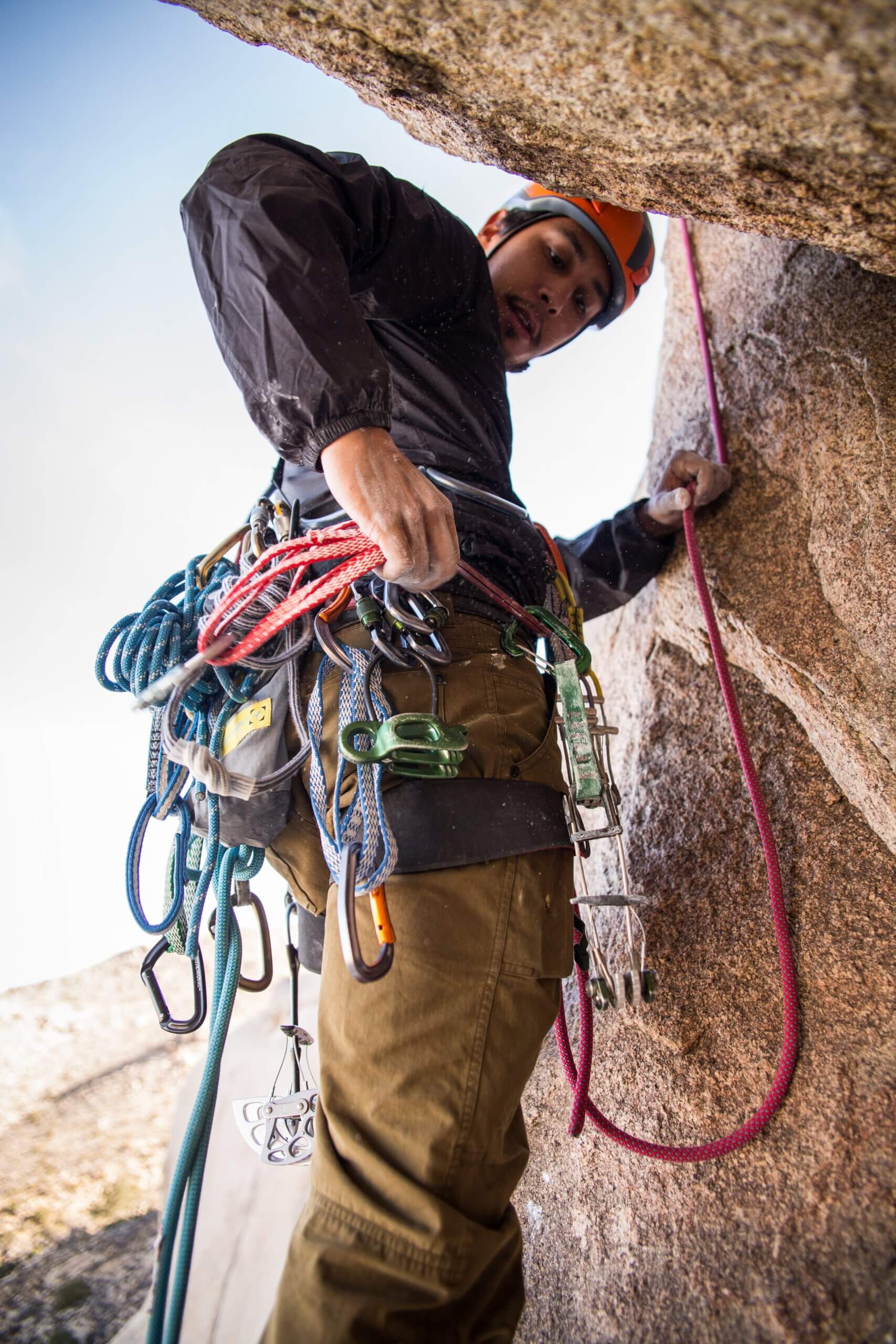 man checking carabiners and gear on climbing harness
